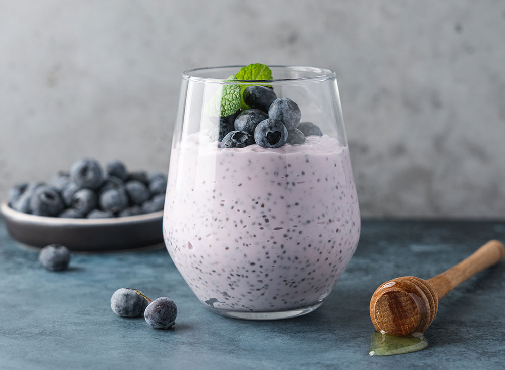 blueberry chia seed pudding in a glass jar with blueberries and mint on top