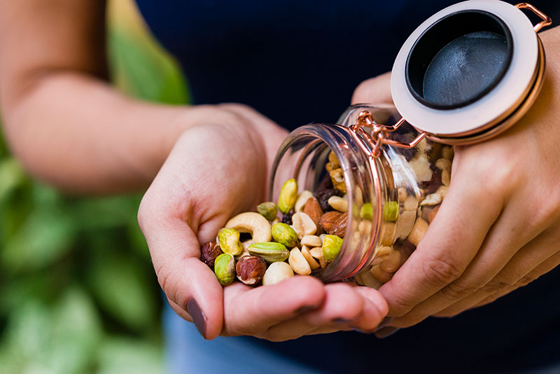 woman cupping trail mix in her hands from a glass mason jar